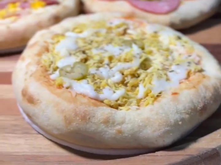 Mini pizzas de vários sabores sobre uma tábua de madeira
