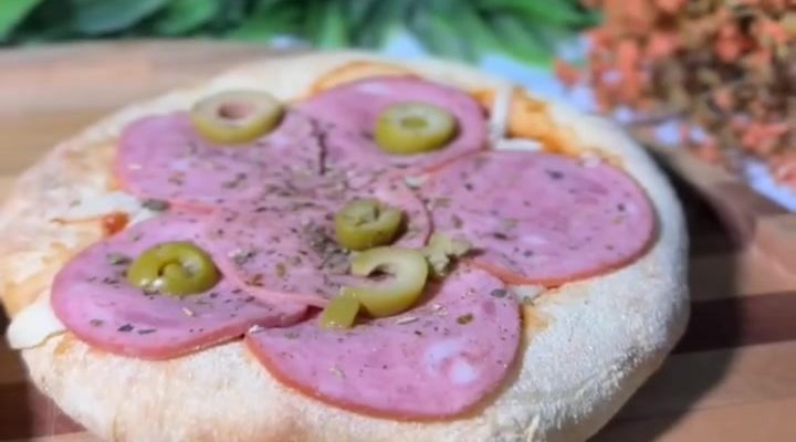 Mini pizza com azeitonas sobre uma tábua de madeira