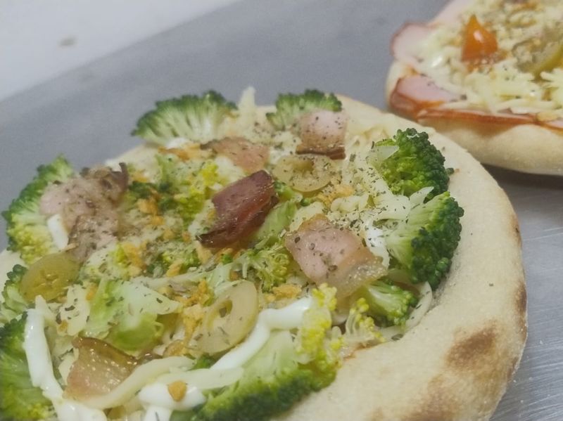 Mini pizza de brócolis com bacon ao lado de uma mini pizza de presunto